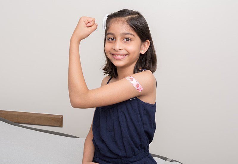 young girl flexing after getting her Covid-19 vaccine