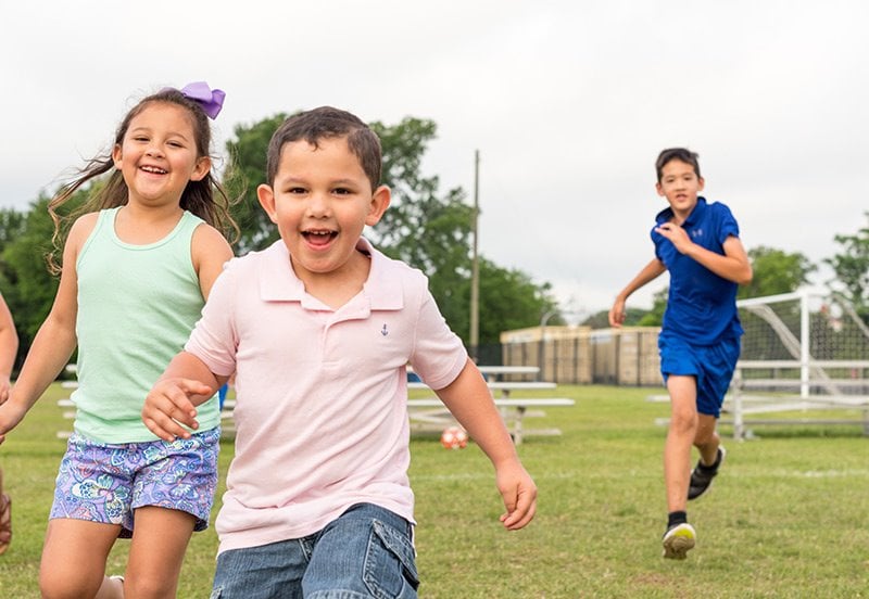 three happy children outside enjoying physical activity