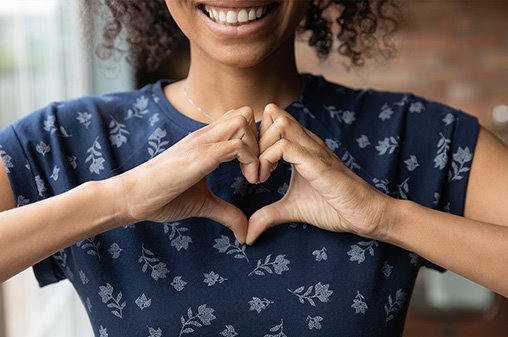 woman smiling while making a heart with her hands